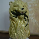 Broc barbotine Lion tenant un lézard dans sa gueule. Fond ocre. Hauteur 20cms