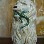 Broc barbotine Lion tenant un lézard dans sa gueule. Fond naturel. Hauteur 20cms