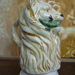Broc barbotine Lion tenant un lézard dans sa gueule. Fond naturel. Hauteur 20cms